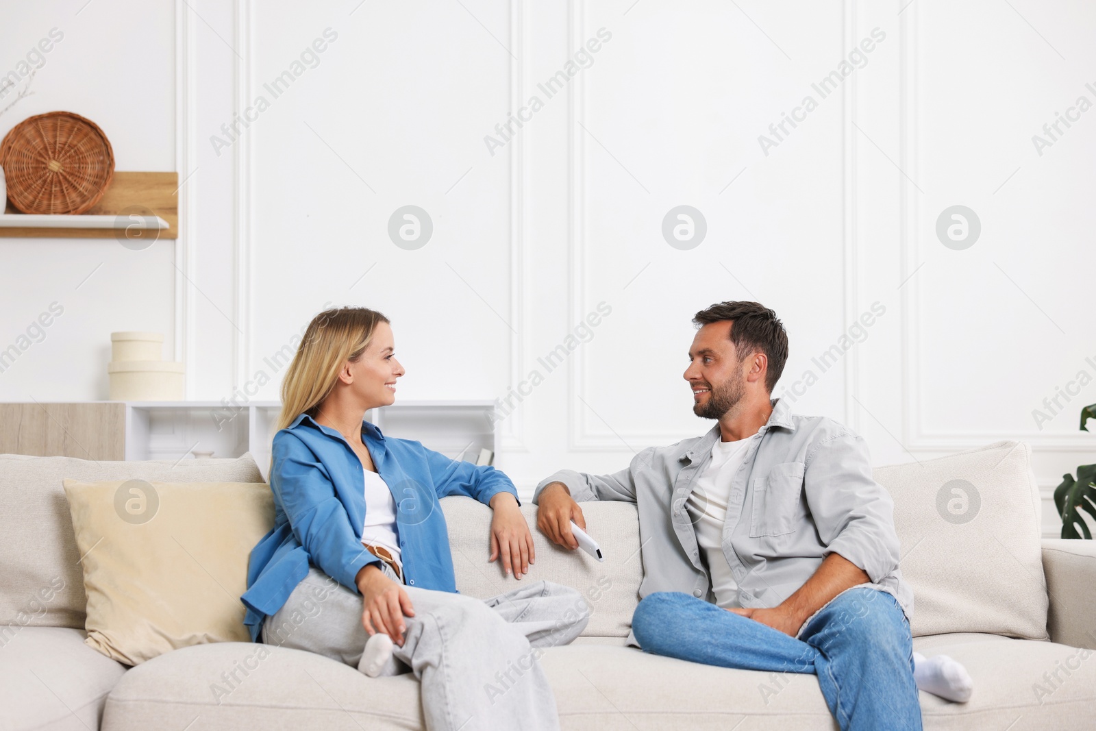 Photo of Couple with air conditioner remote control on sofa at home