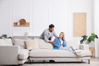 Photo of Happy couple spending time together on sofa at home