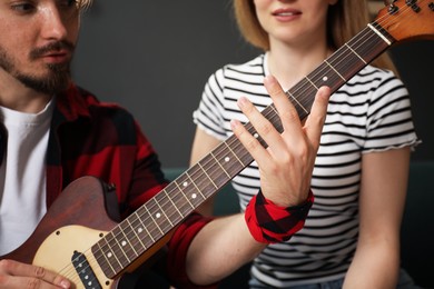 Photo of Tutor teaching woman to play guitar at home, closeup