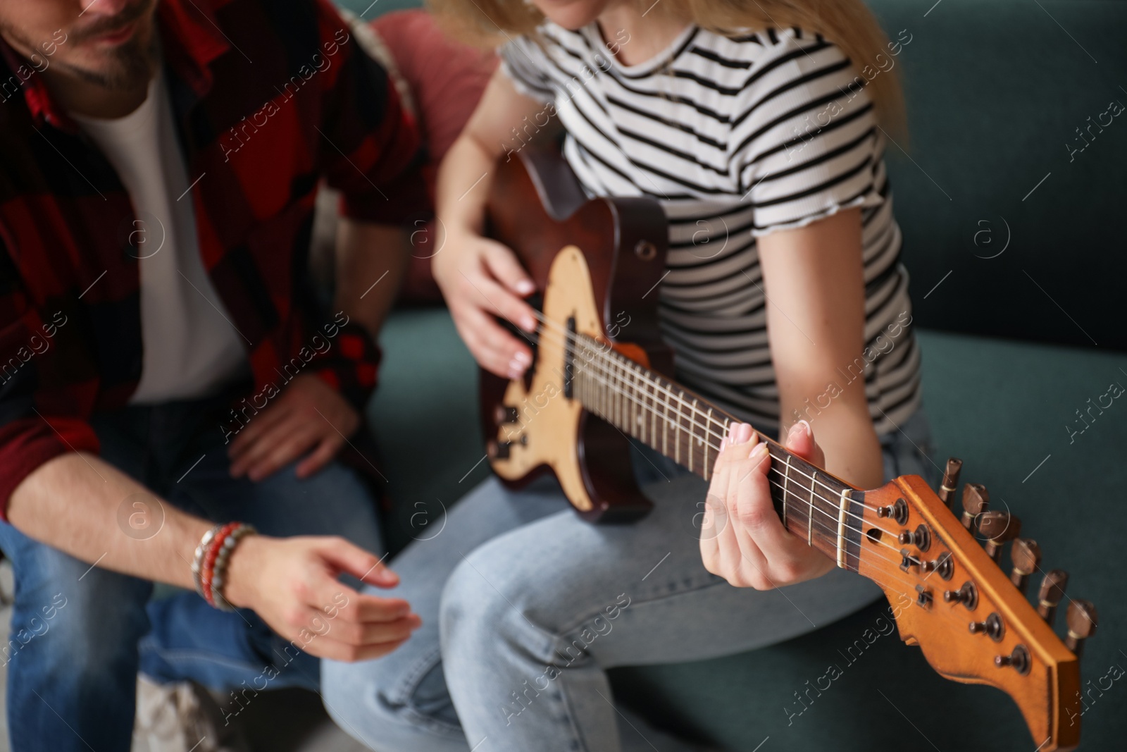 Photo of Tutor teaching woman to play guitar at home, closeup