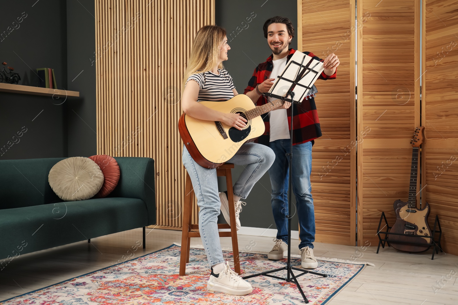 Photo of Tutor teaching woman to play guitar indoors