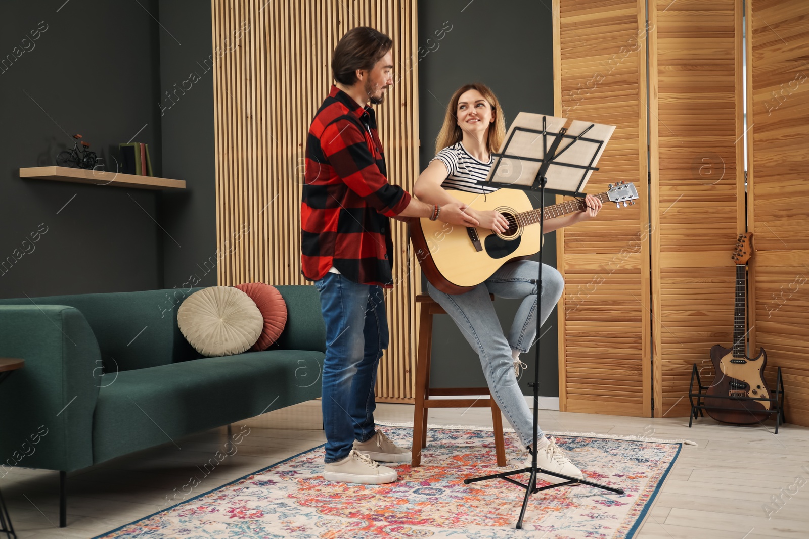 Photo of Tutor teaching woman to play guitar indoors