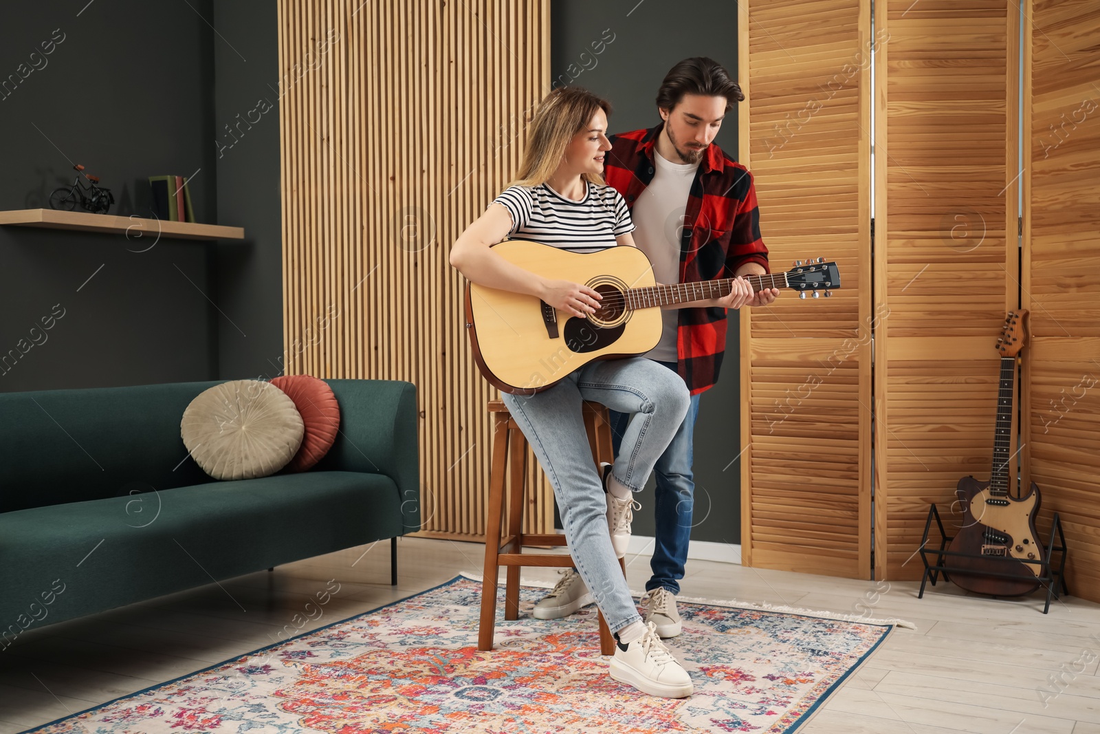Photo of Tutor teaching woman to play guitar indoors