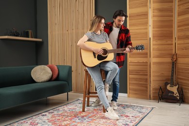 Photo of Tutor teaching woman to play guitar indoors