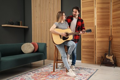 Photo of Tutor teaching woman to play guitar indoors