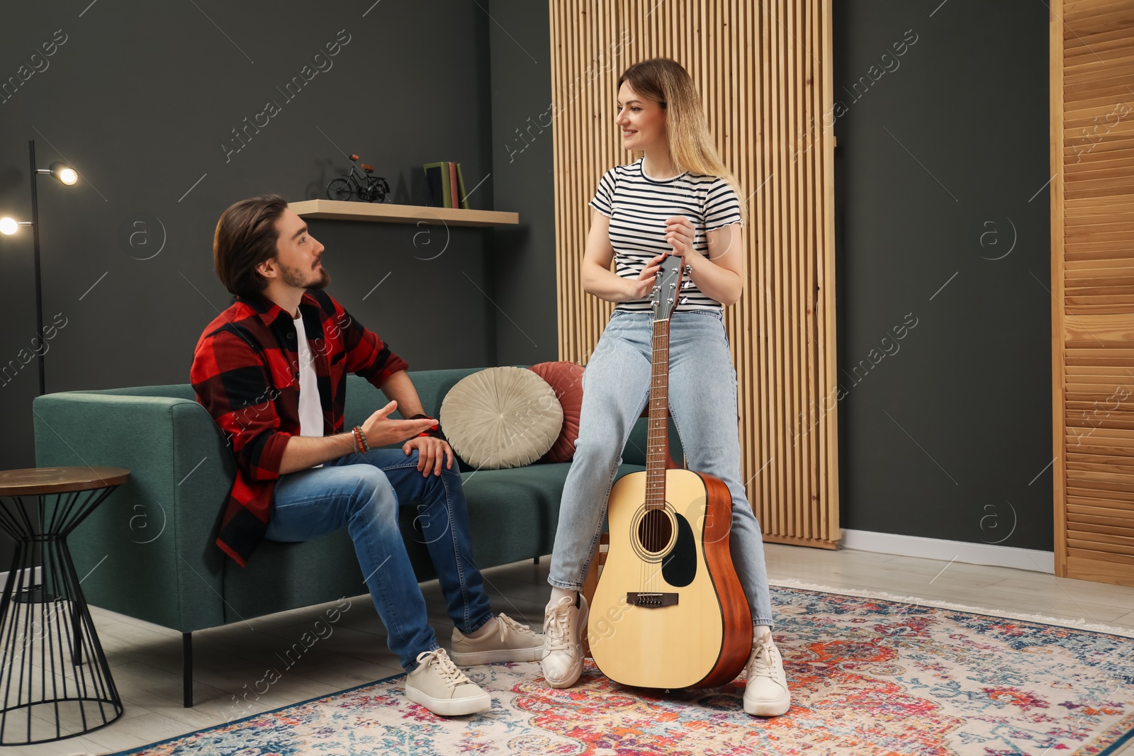 Photo of Tutor teaching woman to play guitar indoors