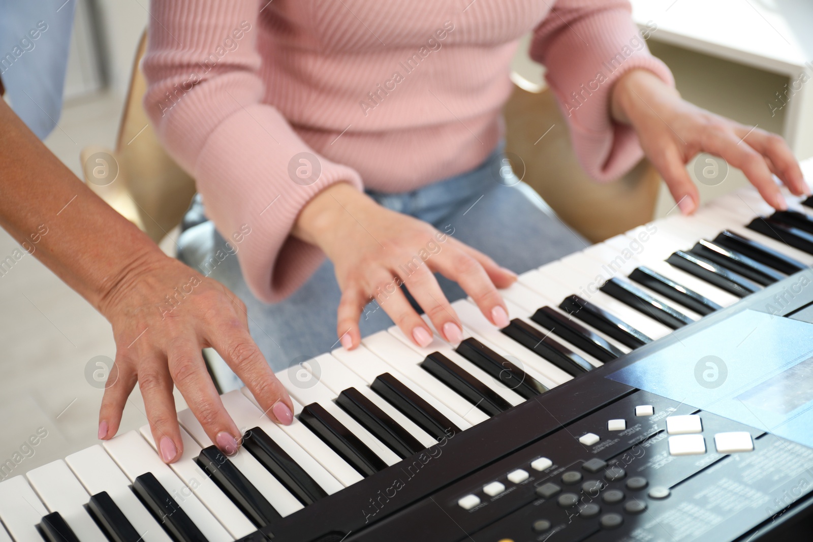 Photo of Tutor teaching woman to play piano indoors, closeup