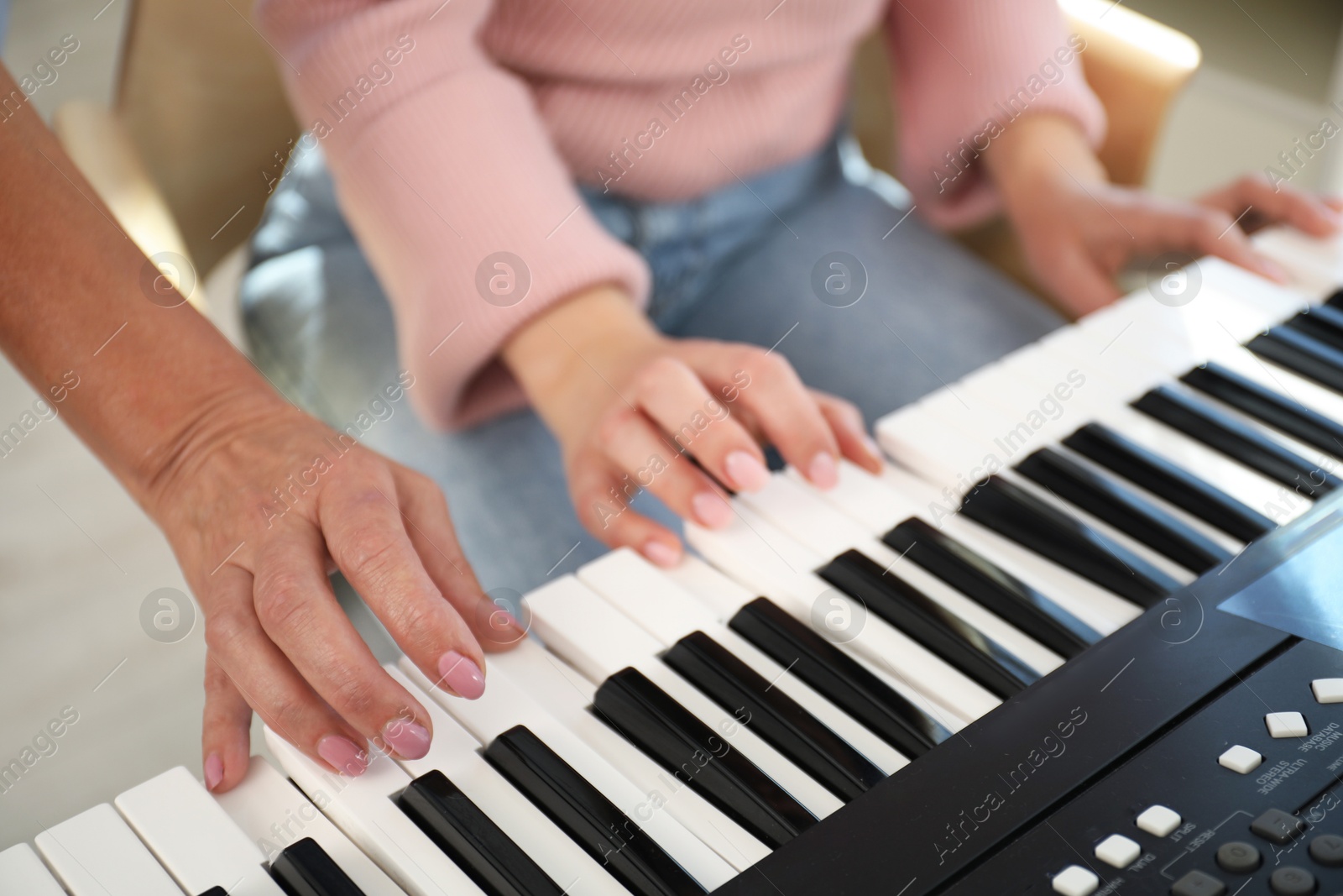 Photo of Tutor teaching woman to play piano indoors, closeup