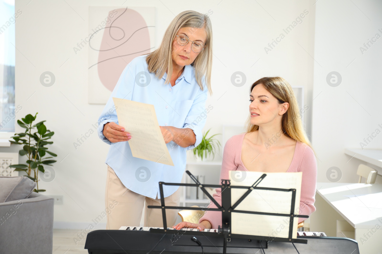 Photo of Tutor teaching woman to play piano indoors