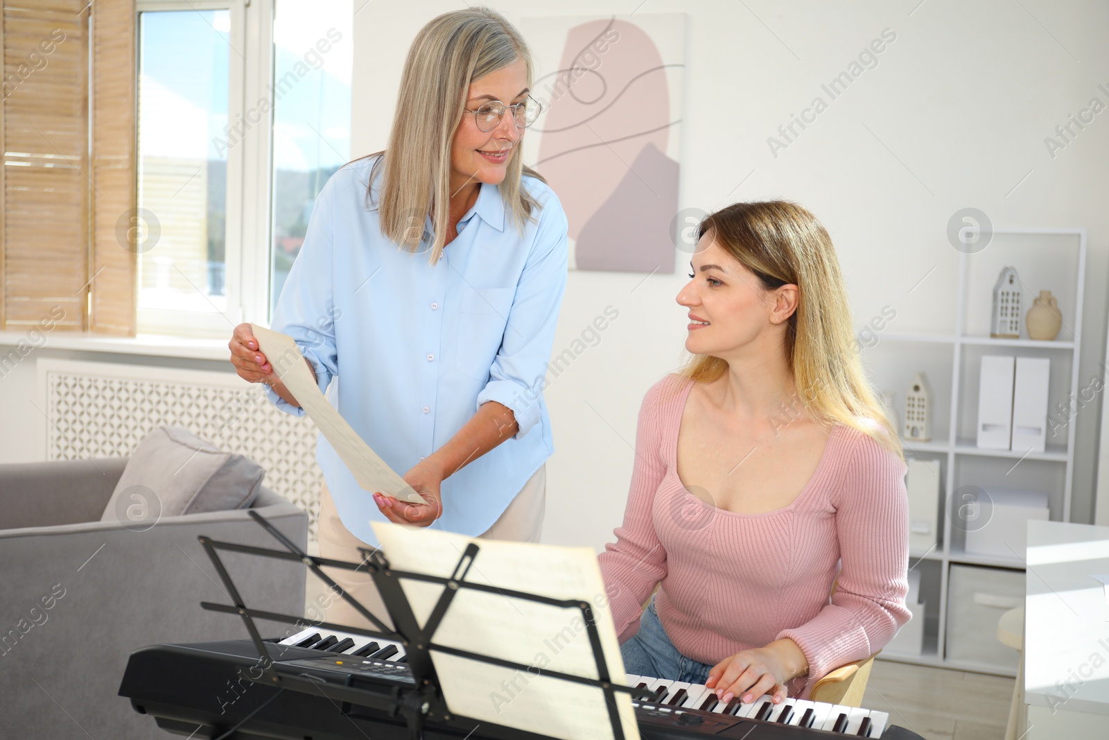Photo of Tutor teaching woman to play piano indoors