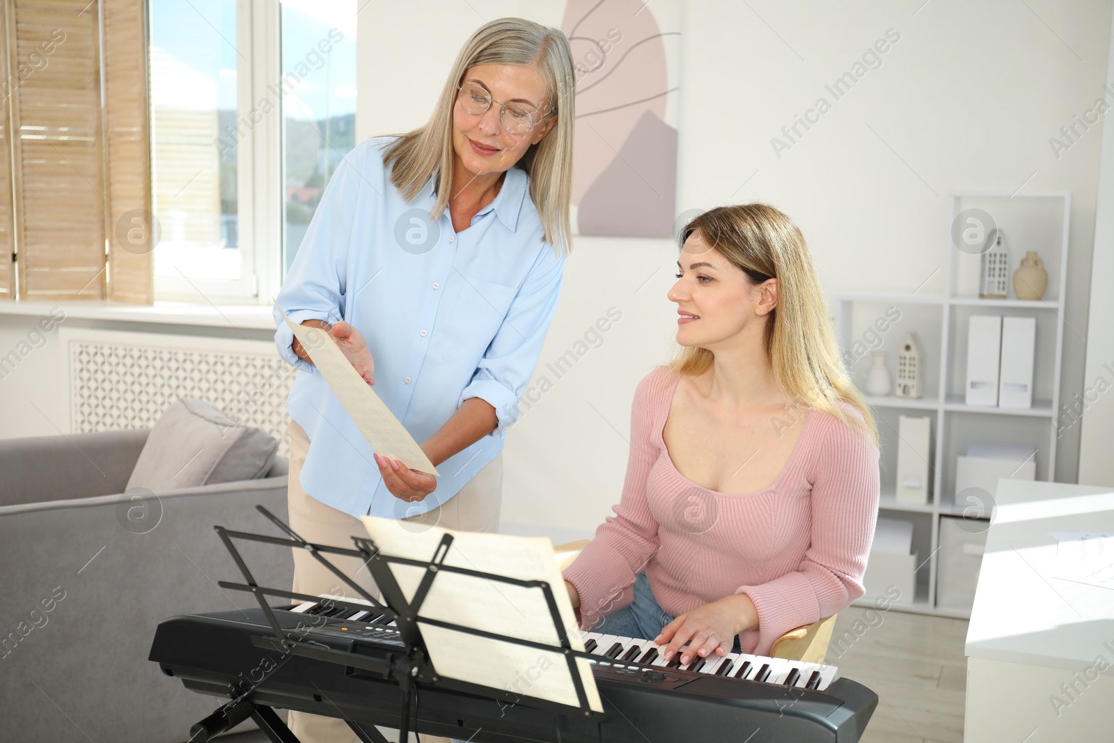 Photo of Tutor teaching woman to play piano indoors