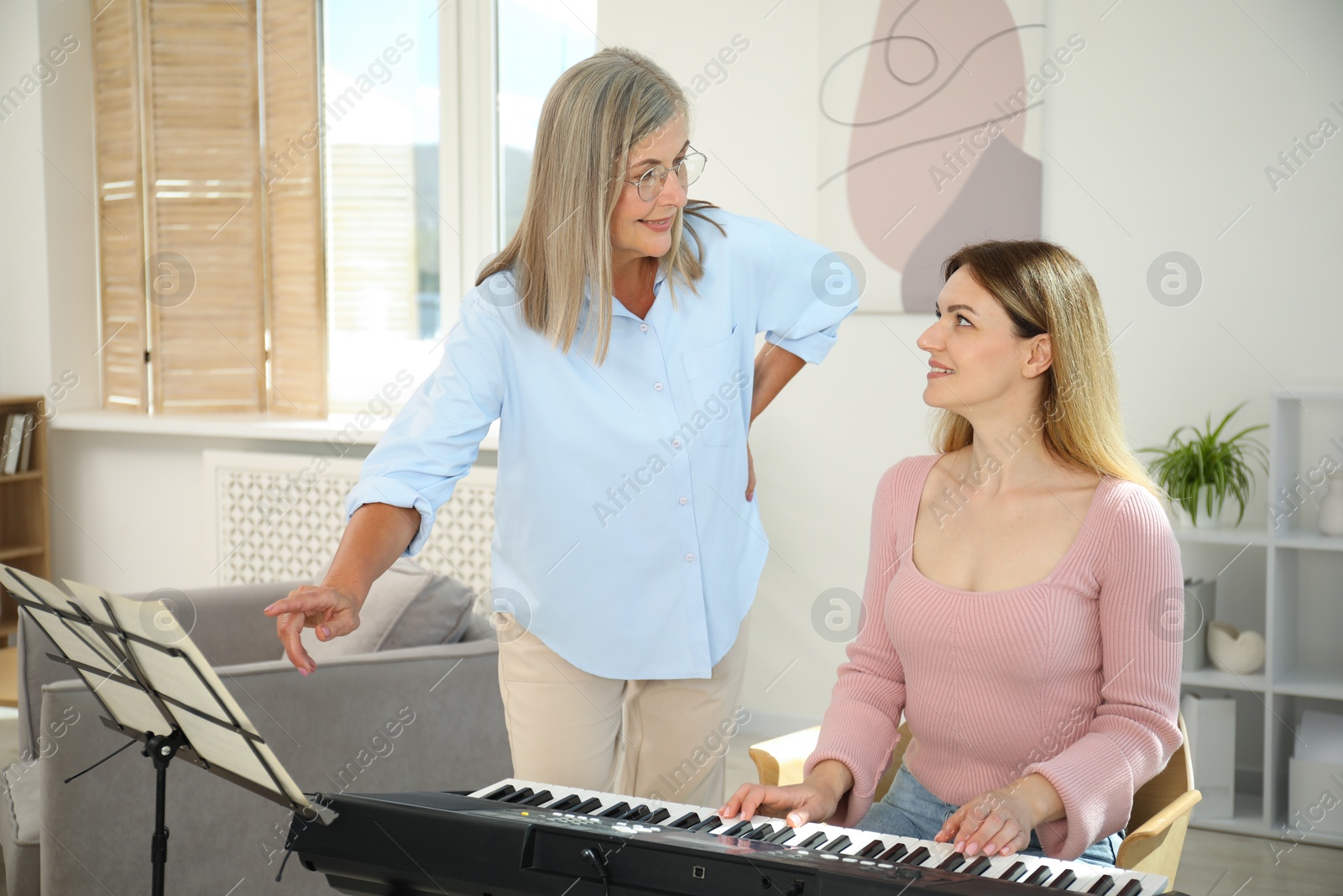 Photo of Tutor teaching woman to play piano indoors