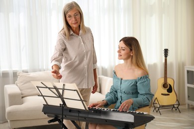 Photo of Tutor teaching woman to play piano indoors