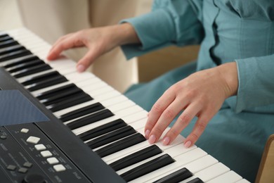 Photo of Woman learning to play piano indoors, closeup