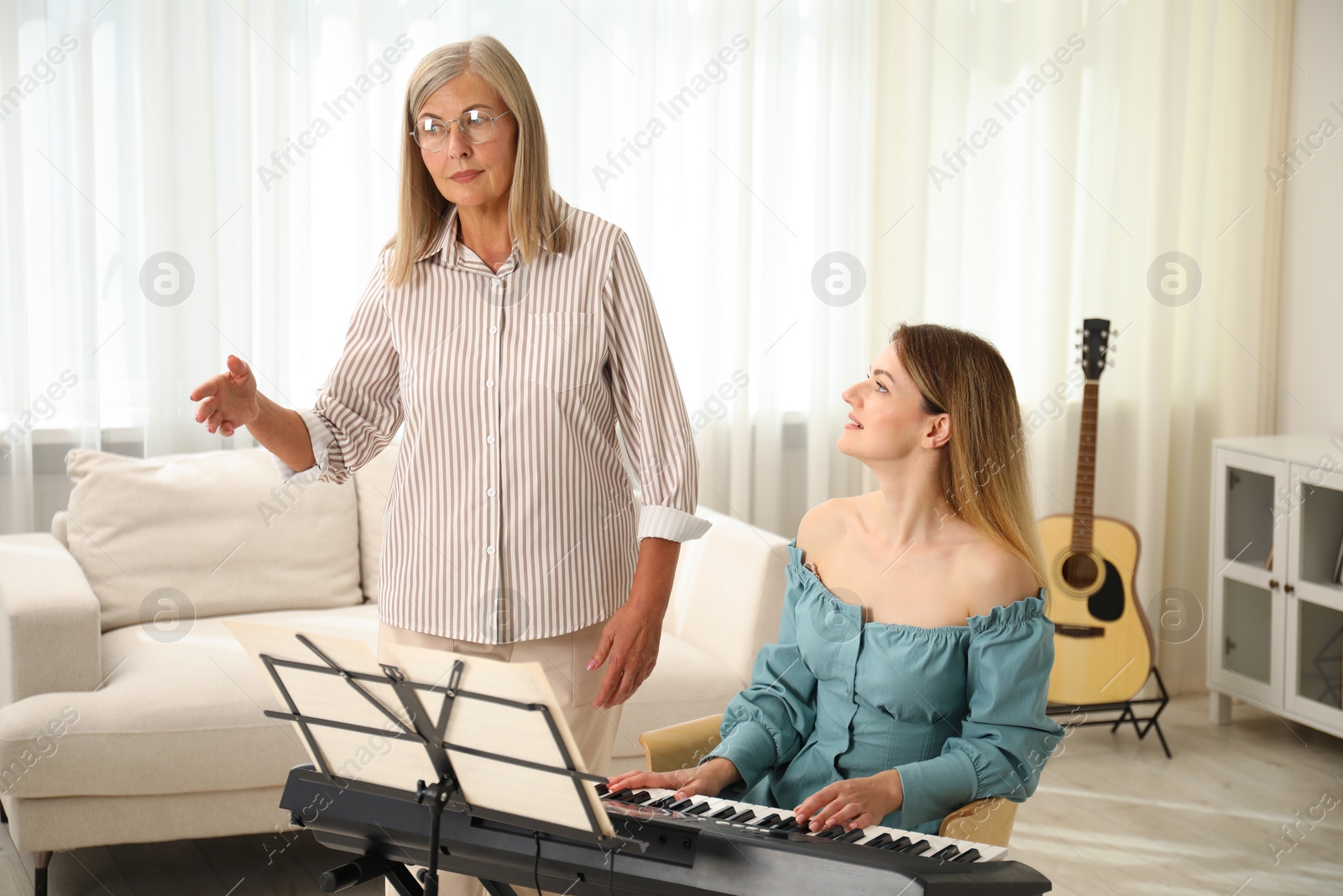 Photo of Tutor teaching woman to play piano indoors
