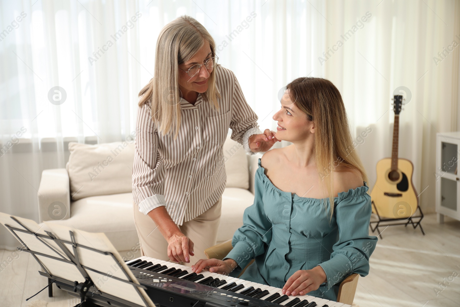 Photo of Tutor teaching woman to play piano indoors