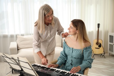 Photo of Tutor teaching woman to play piano indoors