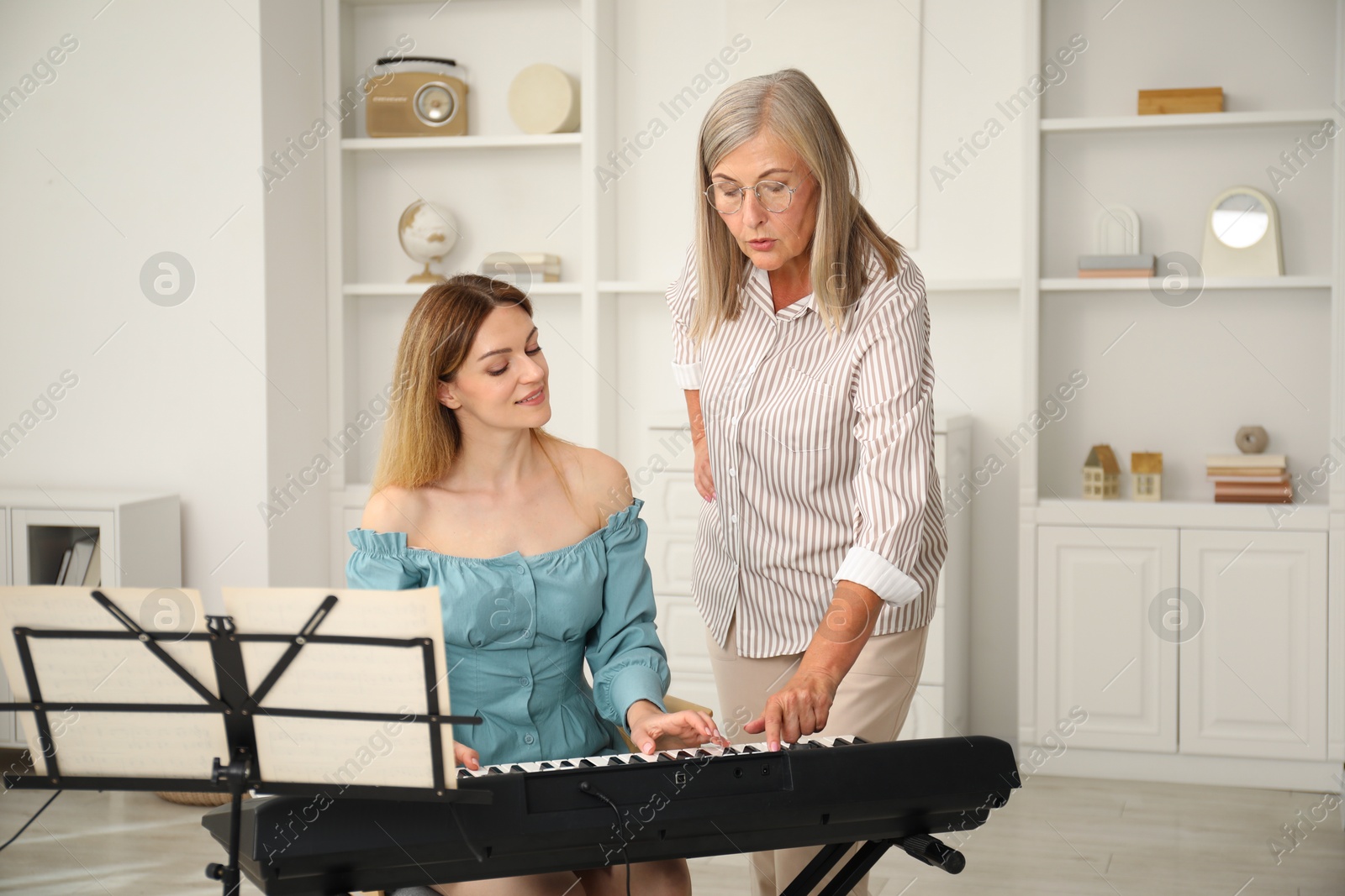 Photo of Tutor teaching woman to play piano indoors
