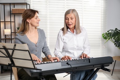 Photo of Tutor teaching woman to play piano indoors