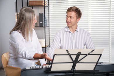 Photo of Tutor teaching man to play piano indoors