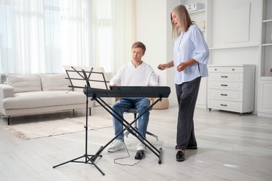 Photo of Tutor teaching man to play piano indoors