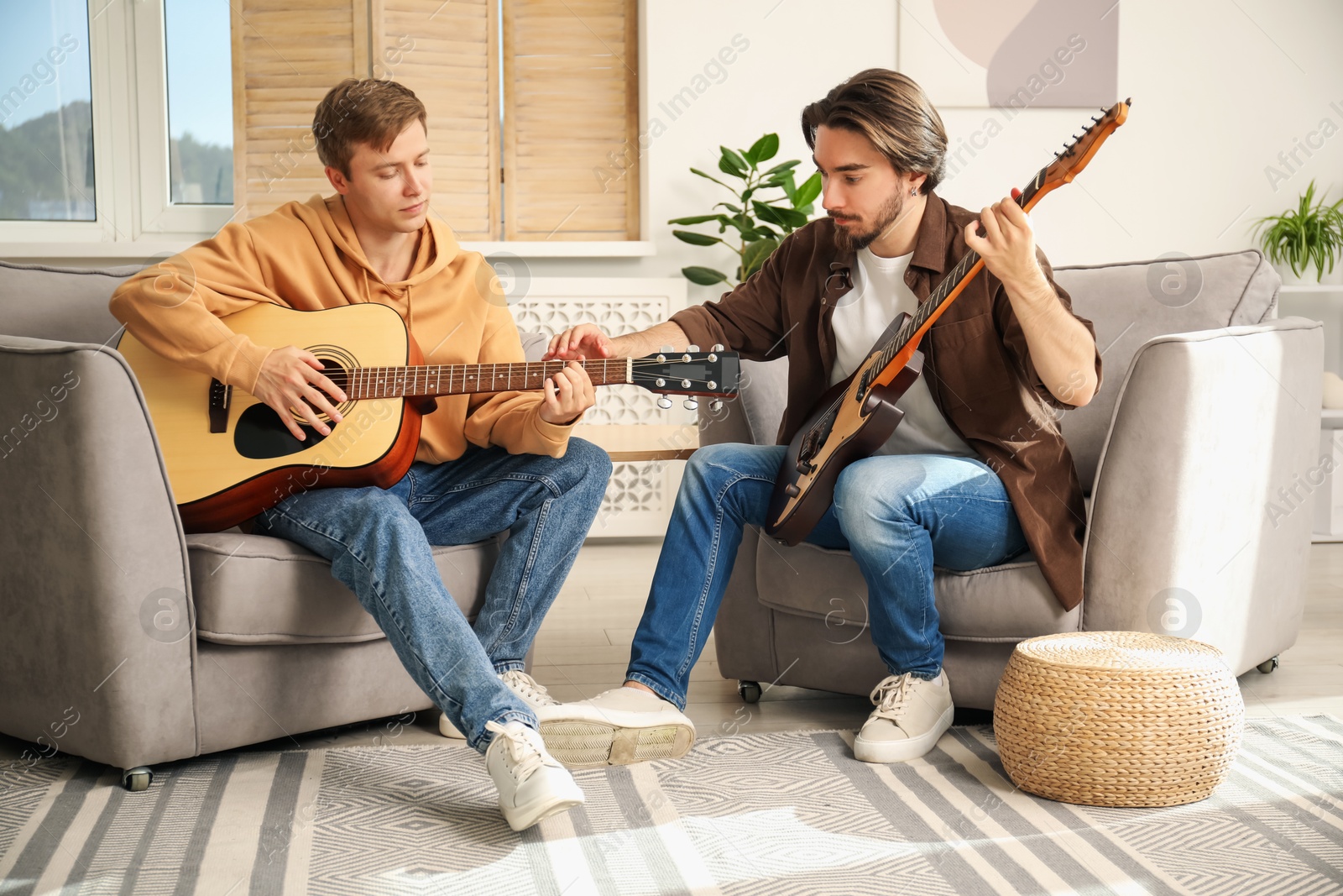 Photo of Tutor teaching man to play guitar at home
