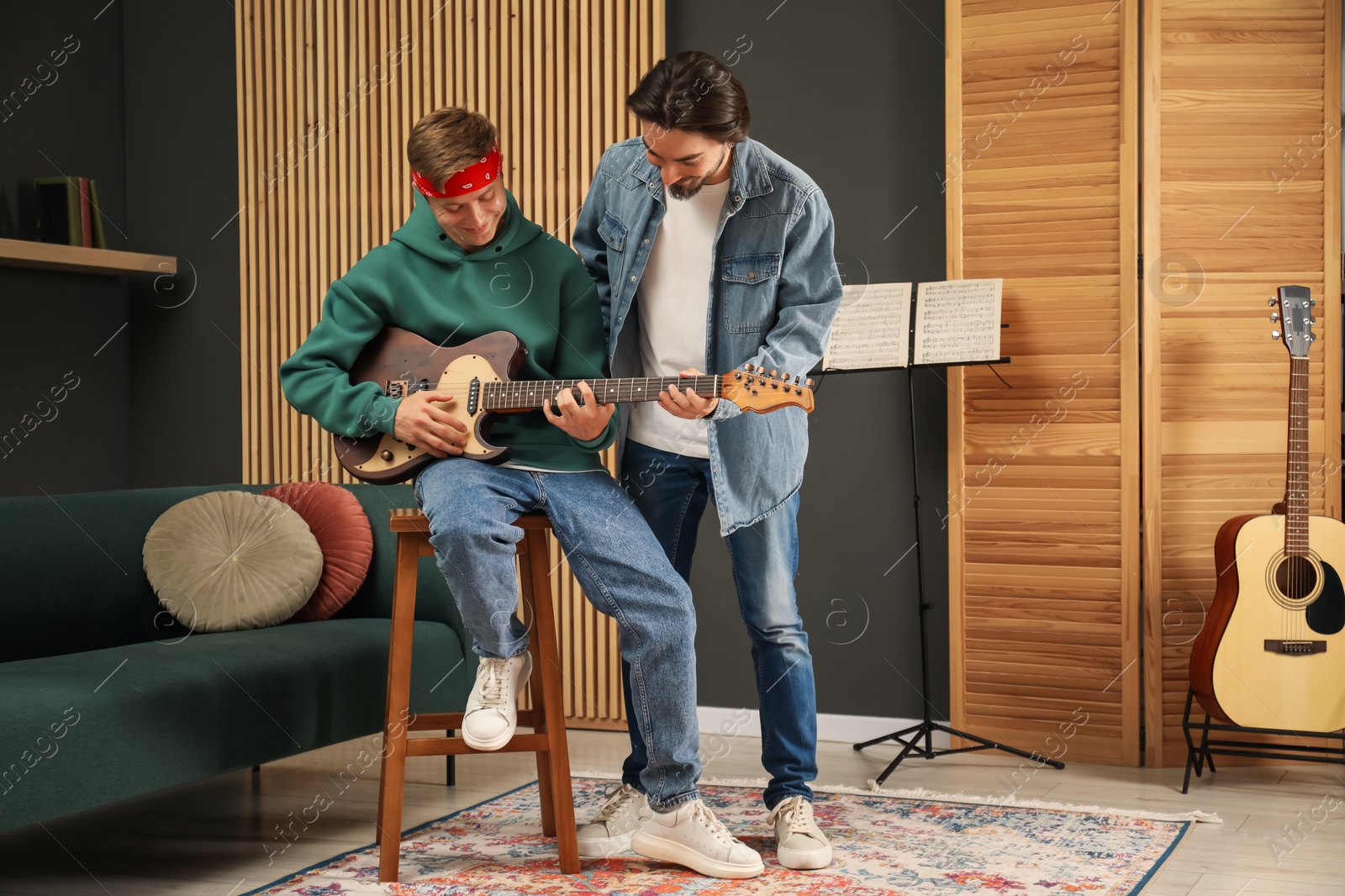 Photo of Tutor teaching man to play guitar indoors