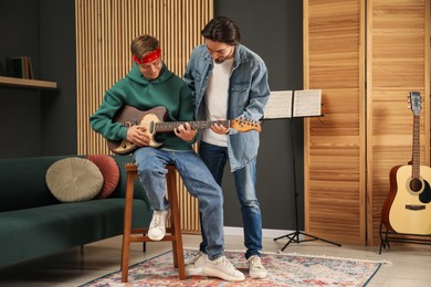 Photo of Tutor teaching man to play guitar indoors