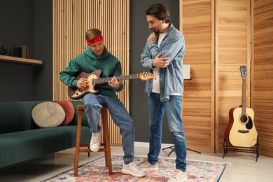 Photo of Tutor teaching man to play guitar indoors