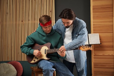 Photo of Tutor teaching man to play guitar indoors