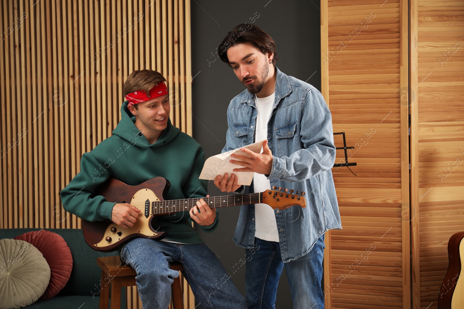 Photo of Tutor teaching man to play guitar indoors