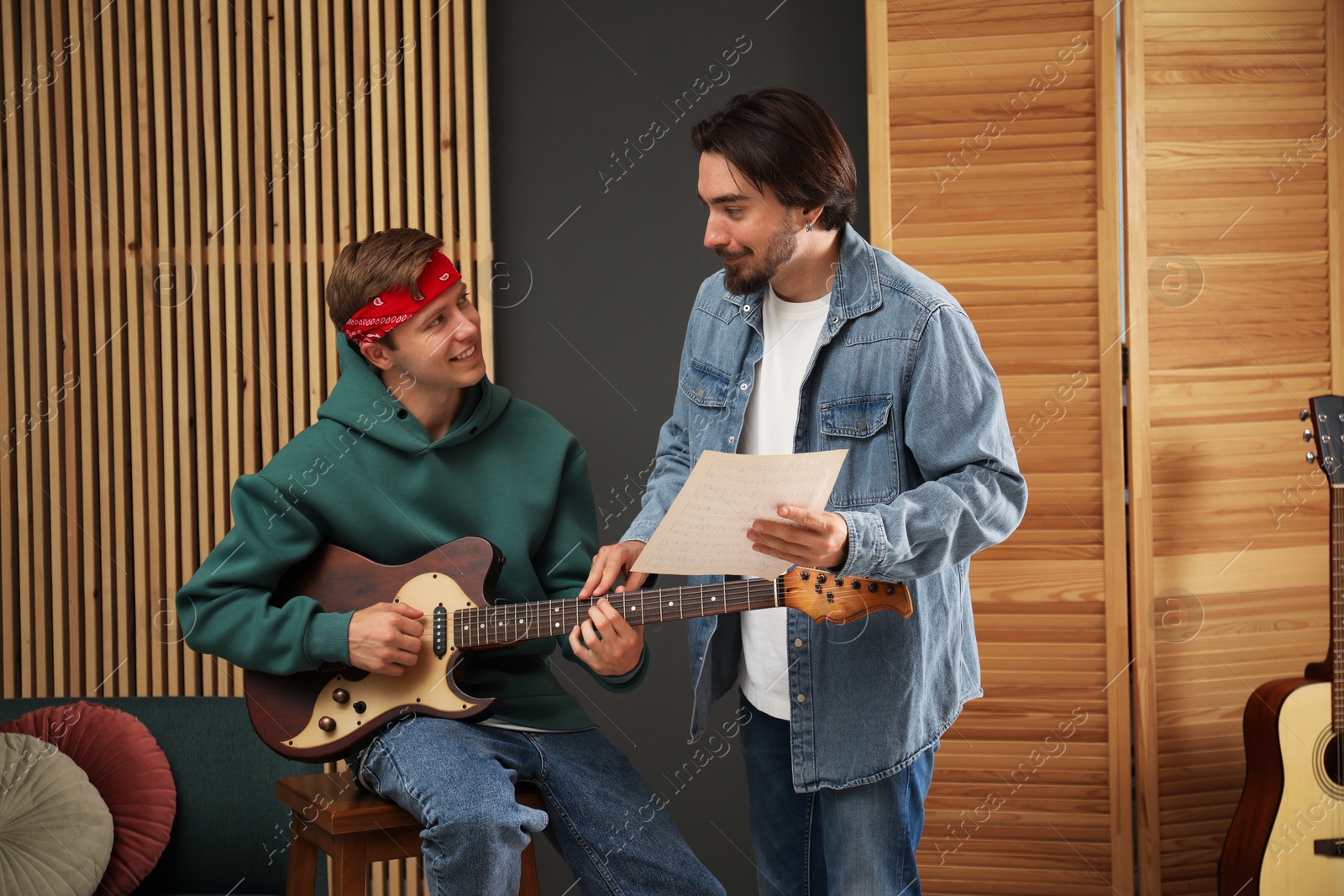 Photo of Tutor teaching man to play guitar indoors