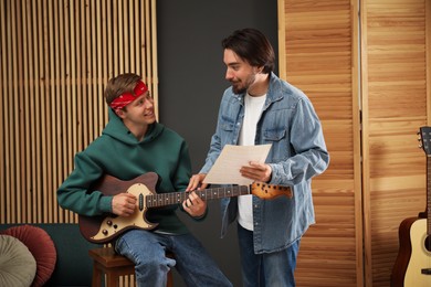 Photo of Tutor teaching man to play guitar indoors