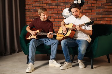 Photo of Tutor teaching man to play guitar indoors