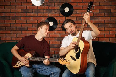 Photo of Tutor teaching man to play guitar indoors