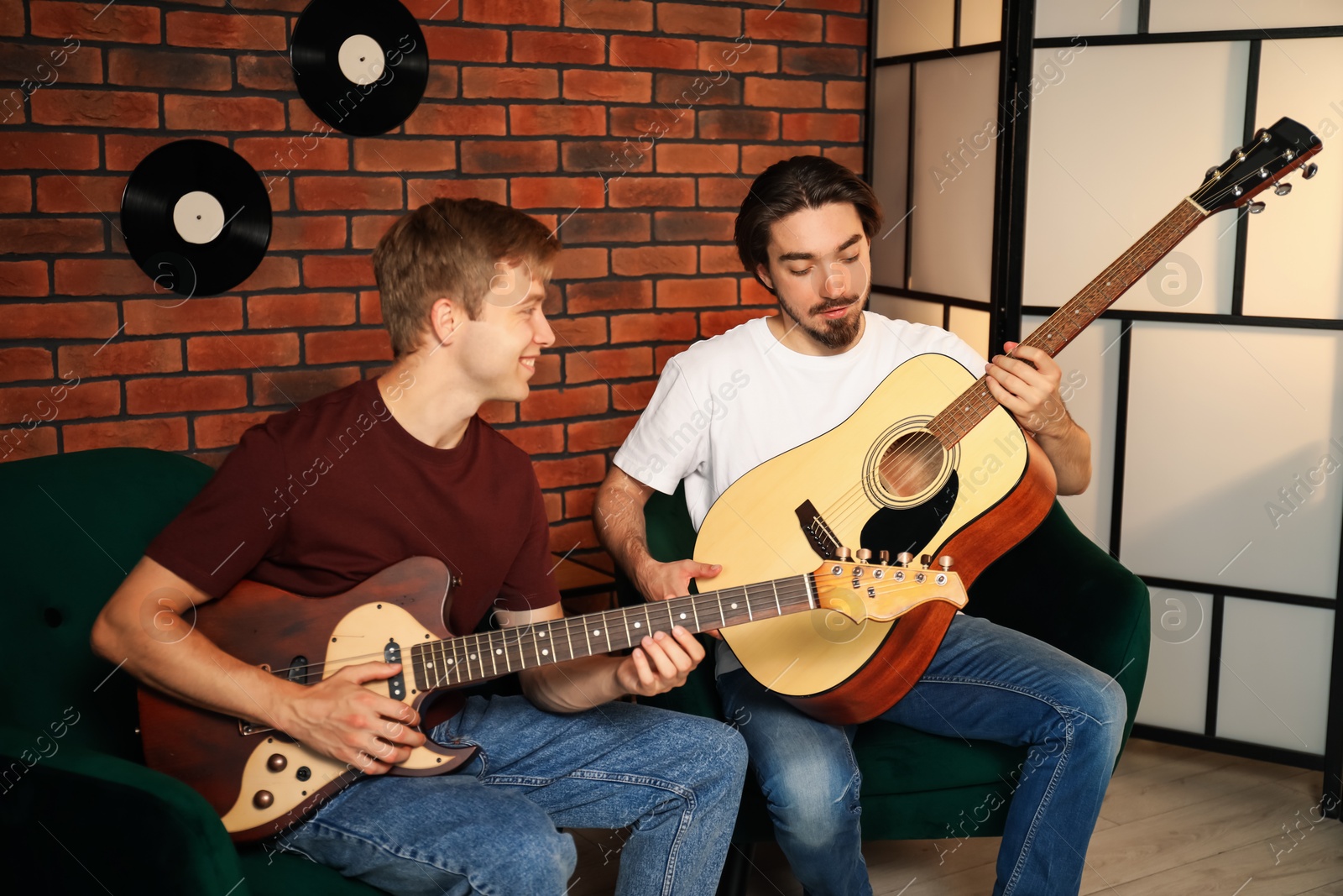 Photo of Tutor teaching man to play guitar indoors