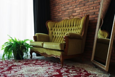 Photo of Green retro sofa, mirror and houseplant in room. Interior design