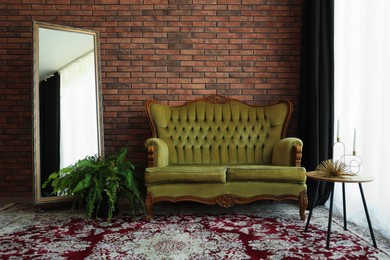 Photo of Green retro sofa, mirror, decor and houseplant in room. Interior design