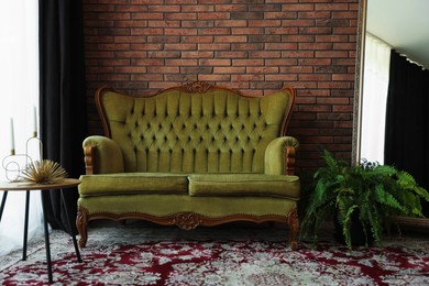 Photo of Green retro sofa, mirror, decor and houseplant in room. Interior design