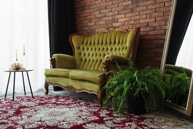 Photo of Green retro sofa, mirror, decor and houseplant in room. Interior design