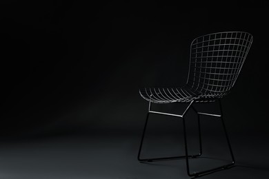 Photo of Stylish chair on black background, space for text. Used stuff