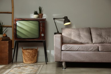 Photo of Soft sofa, retro TV set and other used stuff indoors