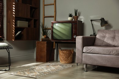 Photo of Soft sofa, retro TV set and other used stuff indoors