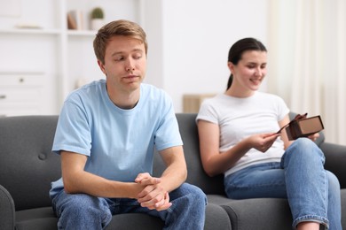 Photo of Man feeling jealous of woman receiving gift at home, selective focus