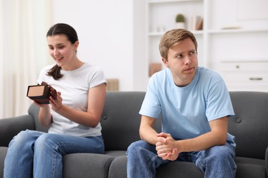 Photo of Man feeling jealous of woman receiving gift at home, selective focus