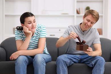 Photo of Woman feeling jealous of man receiving gift at home