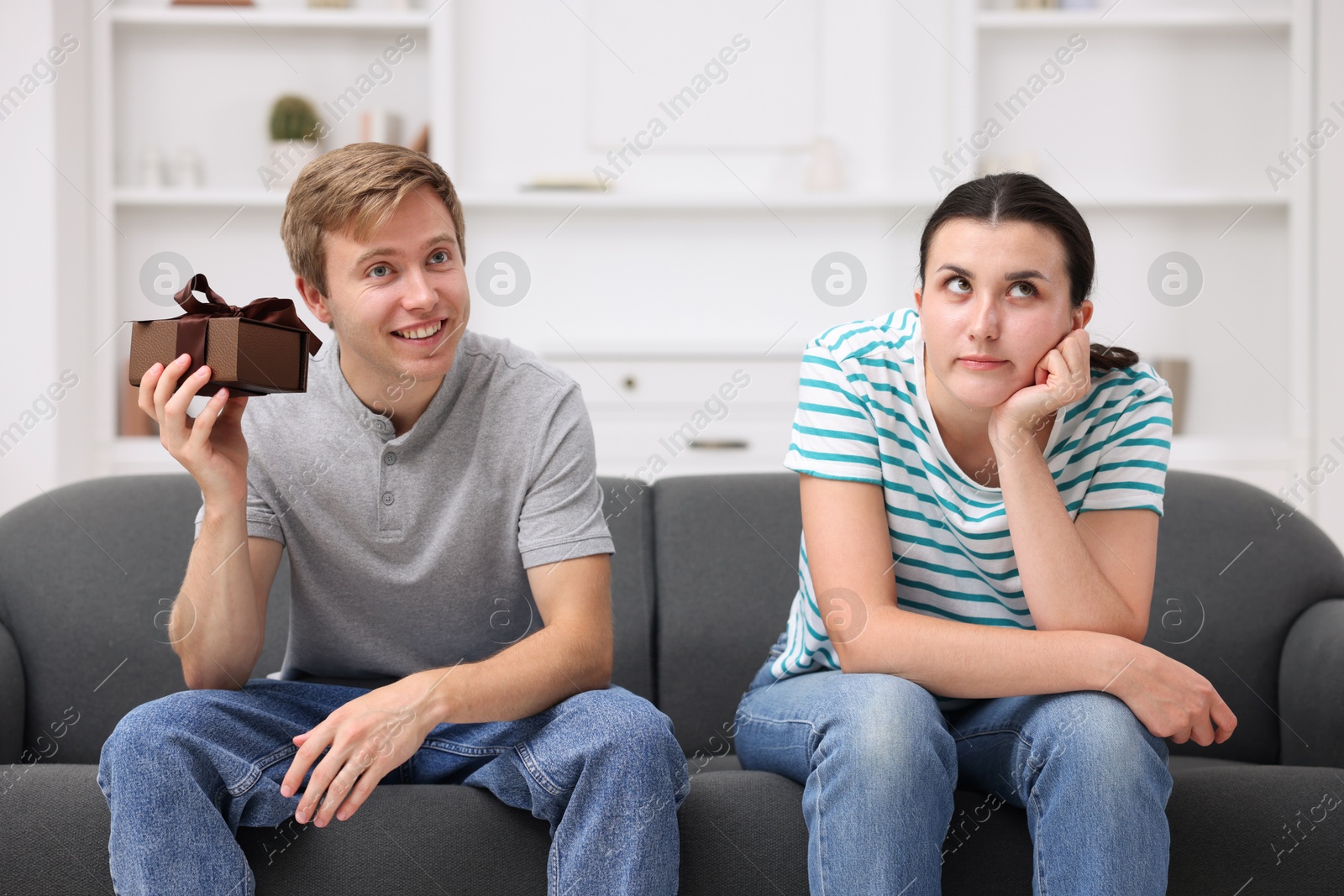 Woman feeling jealous of man receiving gift at home Photo of Woman feeling jealous of man receiving gift at home