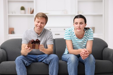 Photo of Woman feeling jealous of man receiving gift at home