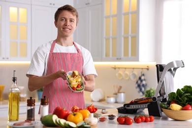 Photo of Man cooking vegetables on electric grill in kitchen