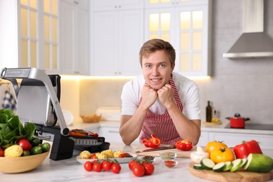 Photo of Man cooking meat and vegetables on electric grill in kitchen